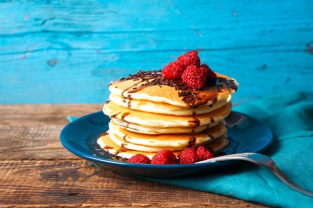 Petit-déjeuner sain crêpes maison avec framboises fraîches et sauce au chocolat sur une vieille table en bois copie espace