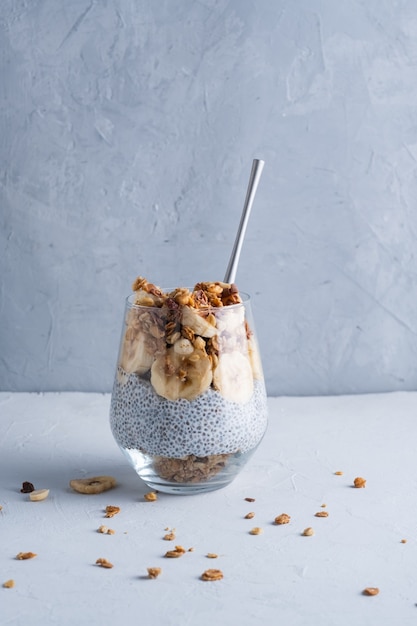 Petit-déjeuner sain dans un verre avec du yogourt aux graines de chio et des noix de banane et du muesli Manger propre