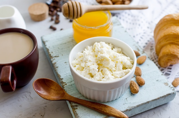 Petit-déjeuner sain avec du fromage cottage ou de la ricotta avec des noix d'amande, du miel et une tasse de café