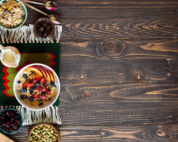 Petit-déjeuner sain avec du lait, du muesli et des fruits, sur une surface en bois.