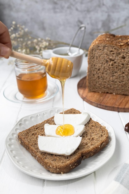 Petit-déjeuner sain avec du pain complet, du fromage de chèvre frais et du miel cru Un délicieux petit-déjeuner