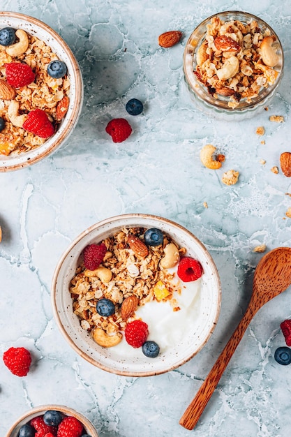 Petit-déjeuner sain avec du yaourt et du granola cuit au four avec des baies dans deux petits bols