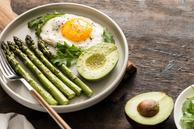 Petit déjeuner sain et fait maison avec asperges, œuf au plat, avocat et roquette. concept de saine alimentation de quarantaine. régime céto