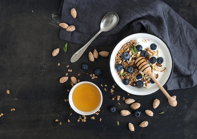 Petit-déjeuner sain Granola d'avoine aux myrtilles fraîches, yogourt aux amandes et menthe dans un bol en métal rustique