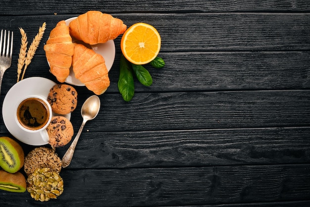 Un petit-déjeuner sain Jus d'orange kiwi croissants biscuits café sur une surface en bois Vue de dessus Espace libre pour le texte