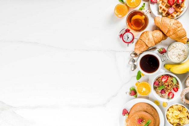 Petit-déjeuner sain manger concept divers aliments du matin - crêpes gaufres croissant sandwich à l'avoine et granola avec yaourt fruits baies café thé jus d'orange fond blanc