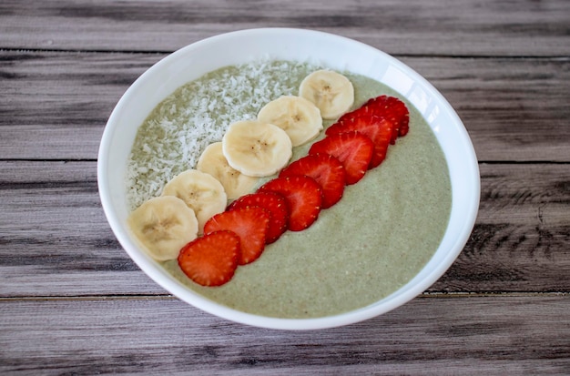 Un petit-déjeuner sain Mélange de smoothie vert aux baies garni de farine de noix de coco fraises bananes