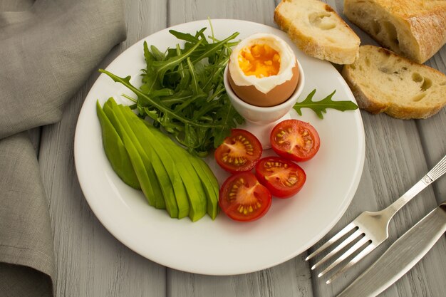 Petit-déjeuner sain avec des œufs durs et des légumes sur la plaque blanche