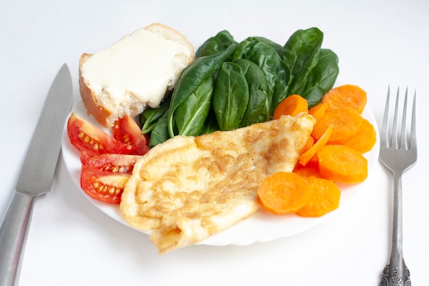 Petit-déjeuner sain, omelette, légumes, sandwich au fromage à pâte molle, couteau et fourchette, isolé sur fond blanc