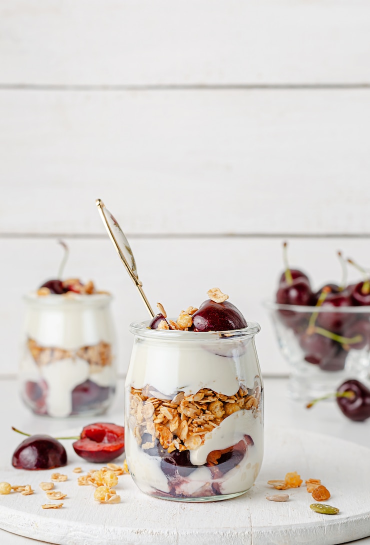 Photo petit-déjeuner sain. parfait granola aux cerises sur fond de bois blanc.