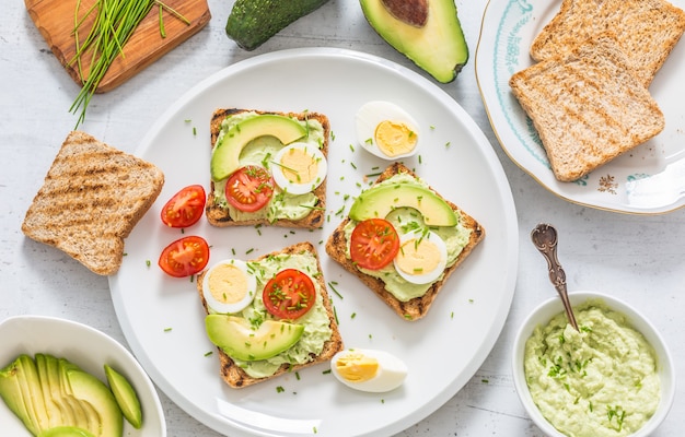 Petit-déjeuner sain à partir de toasts à l'avocat tartinable guacamole oeuf tomate et ciboulette.