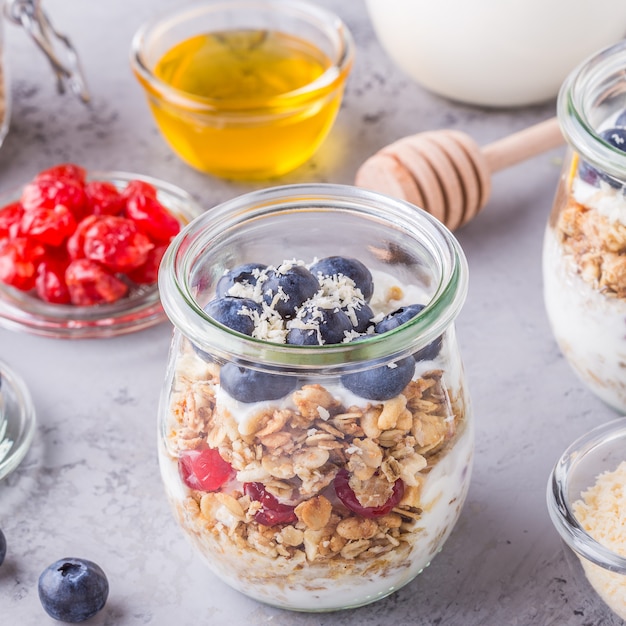 Petit-déjeuner sain - pots en verre de flocons d'avoine avec des fruits frais, du yaourt et du miel.