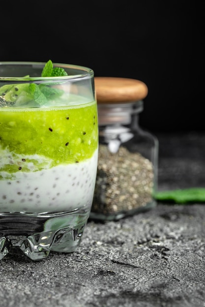 Petit-déjeuner sain pudding de chia avec kiwi dans des bocaux en verre sur un tableau blanc Propre alimentation régime alimentaire végétalien concept image verticale