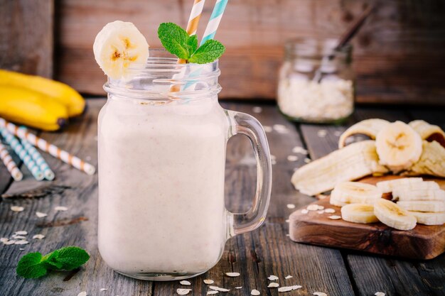 Petit-déjeuner sain smoothie à la banane avec de la farine d'avoine dans un bocal en verre sur un fond en bois