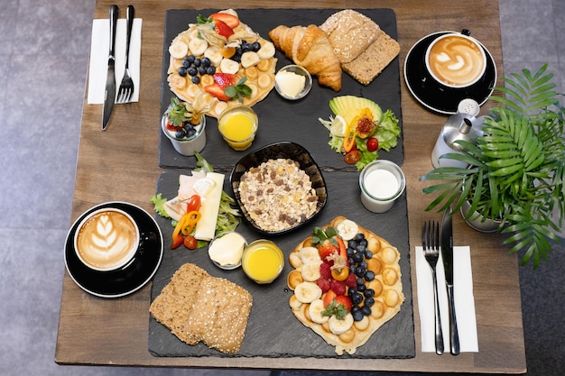Petit-déjeuner sain sur la table avec café jus d'orange fruits gaufres et croissantsxA