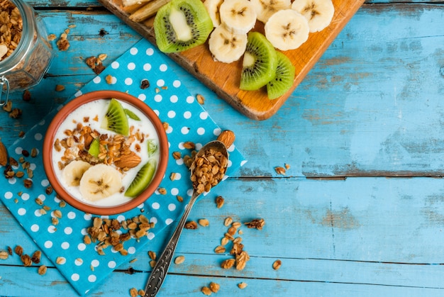 Petit-déjeuner sain: yaourt avec granola, banane et kiwi