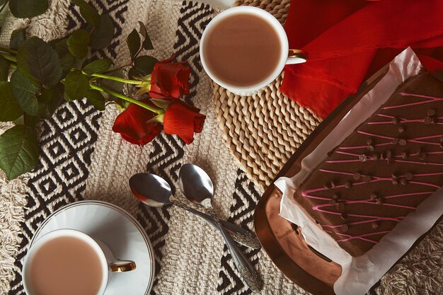 Petit-déjeuner de la saint-valentin avec des tasses à café au gâteau au chocolat et des roses rouges esthétiques à plat