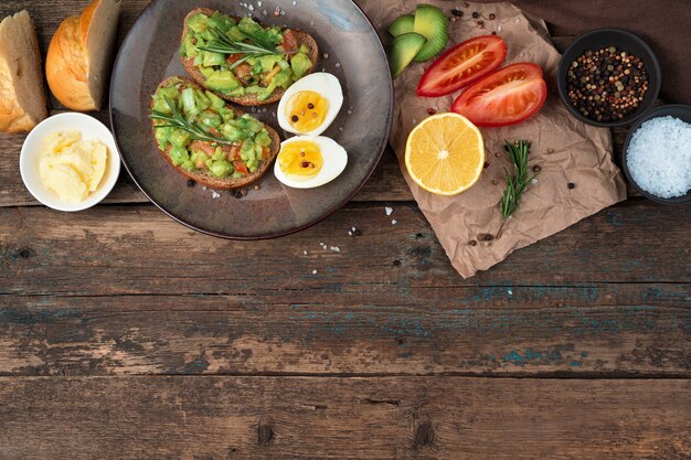 Petit-déjeuner avec des sandwichs à l'avocat sur un fond en bois.