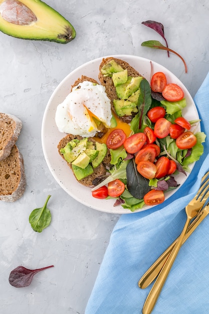 Petit-déjeuner santé avec toasts à l&#39;avocat, œuf poché et salade