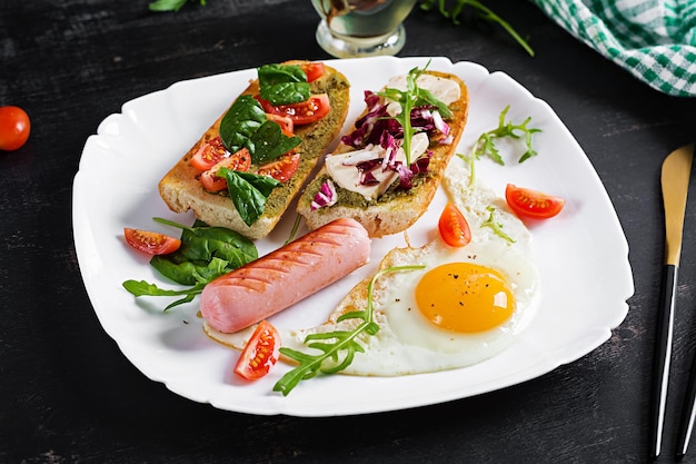 Petit-déjeuner Saucisse aux œufs frits et sandwichs au pesto tomates au fromage vert