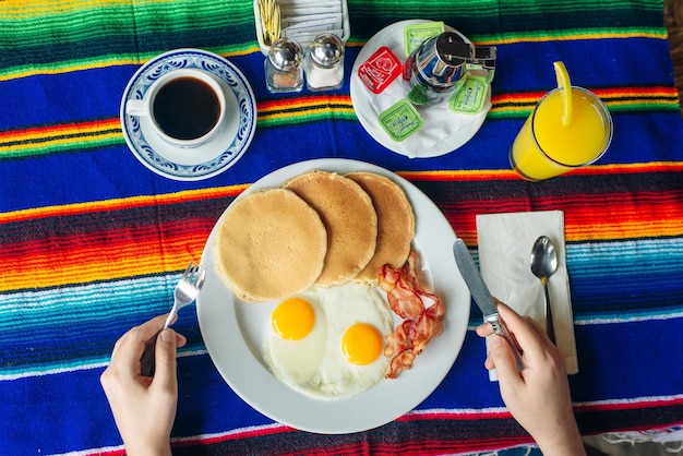 Petit-déjeuner savoureux avec crêpes œufs frits et bacon sur table