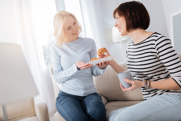 Petit déjeuner savoureux. Ravi de belles femmes positives qui se regardent et sourient tout en prenant un délicieux petit-déjeuner ensemble