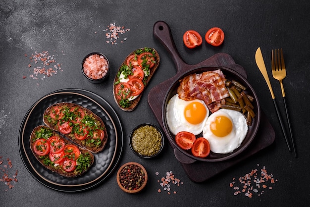 Un petit-déjeuner savoureux se compose d'œufs, de haricots, de bacon, de tomates, d'épices et d'herbes