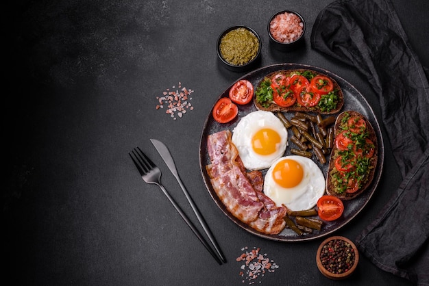 Un petit-déjeuner savoureux se compose d'œufs, de haricots, de bacon, de tomates, d'épices et d'herbes