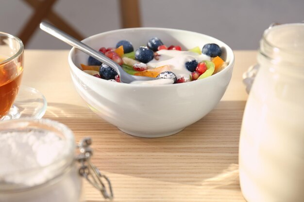 Photo petit-déjeuner savoureux avec yaourt frais et fruits sur table en bois