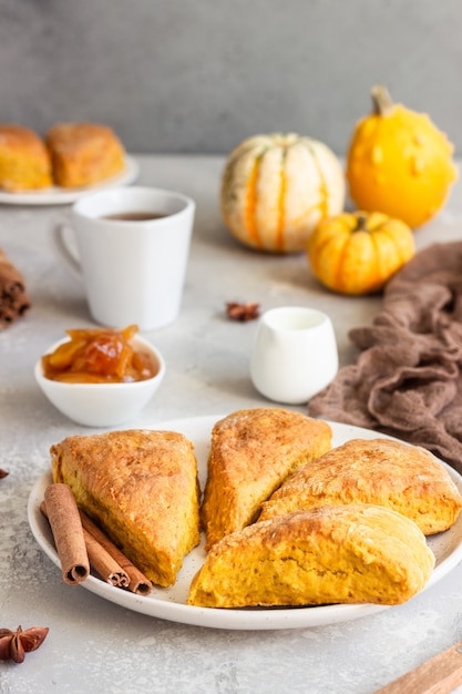 Petit-déjeuner avec des scones de citrouille épicés, une tasse de thé et du lait.