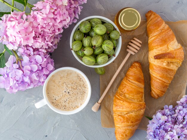 Petit déjeuner servi café et croissants près de fleurs