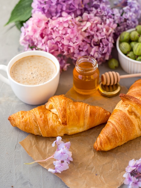 Petit déjeuner servi café et croissants près de fleurs