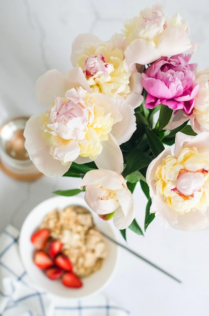 Petit-déjeuner servi avec granola et bouquet de pivoine