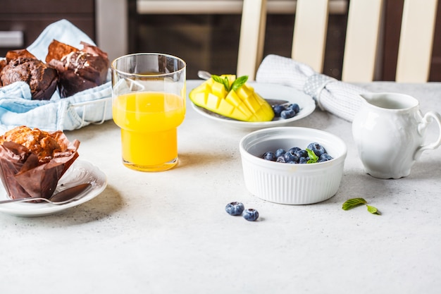 Petit déjeuner servi avec muffins, jus de fruits, baies et fruits.