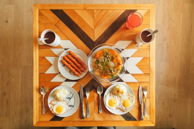 Petit-déjeuner simple fait maison composé d'œufs au plat et de saucisses le matin.