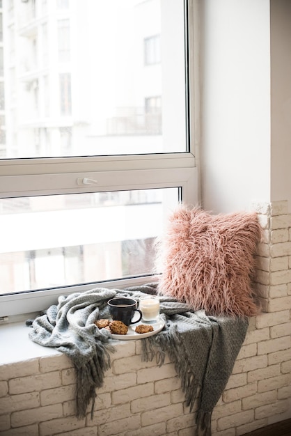 Petit-déjeuner de style scandinave tasse de café et biscuits sur un rebord de fenêtre confortable avec une couverture chaude