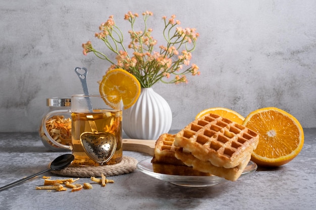 Petit-déjeuner sucré composé de gaufres et d'un verre de thé chaud à l'orange