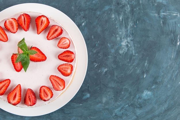 Petit-déjeuner sucré délicieux gâteau au fromage avec des fraises fraîches et une recette maison à la menthe sans cuisson sur une table en pierre bleu foncé Copier l'espace