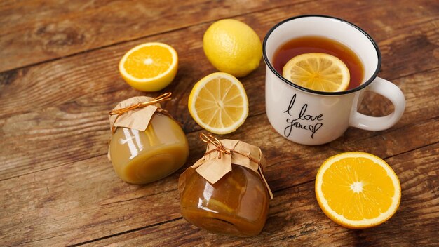 Petit-déjeuner sucré Tasse de thé noir au citron Citrons et pots de confiture maison sur une table en bois