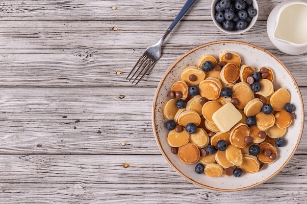 Petit déjeuner tendance avec mini crêpes, myrtilles et pépites de chocolat, vue de dessus.