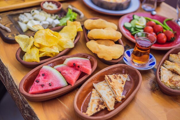 Photo petit-déjeuner turc table pâtisseries légumes verts olives fromages oeufs frits épices confitures miel thé