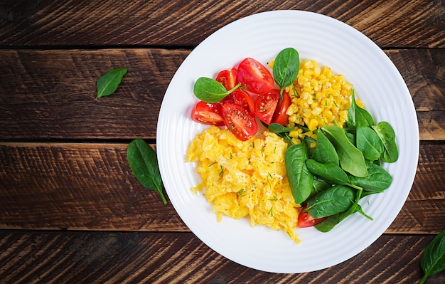 Petit-déjeuner. Œufs brouillés aux tomates cerises, épinards et maïs.