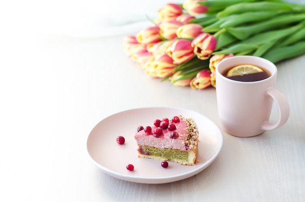 Petit déjeuner, vacances, matin avec tulipes fleurs, gâteau, thé, café dans une tasse rose sur une surface claire