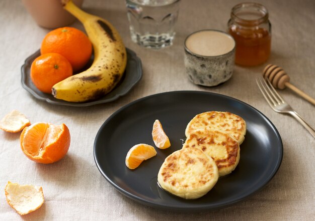 Petit-déjeuner végétarien de crêpes de quark au miel, aux fruits et au café au lait. Style rustique.