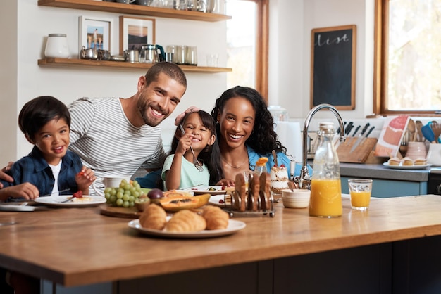Le petit-déjeuner vous mettra de bonne humeur Photo d'une famille de quatre personnes prenant son petit-déjeuner ensemble à la maison