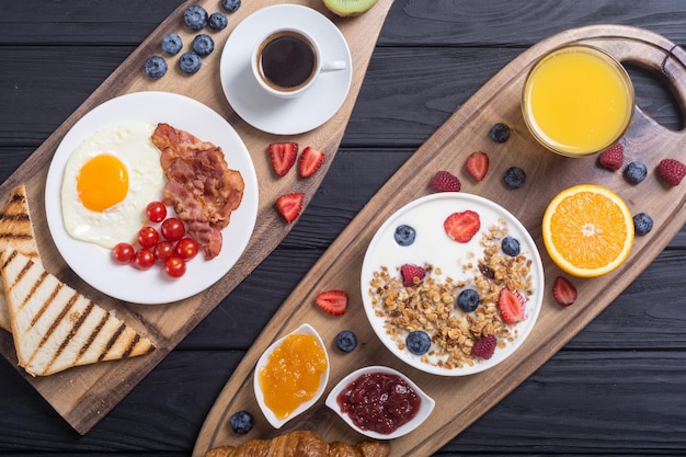 Petit déjeuner avec yogourt, œufs, baies, jus de croissant et confiture.