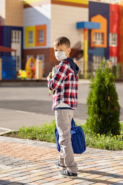 Un petit écolier portant un masque médical va à l'école.