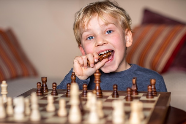 Petit enfant de 5 ans jouant aux échecs sur un grand échiquier Échiquier sur table devant le garçon pensant au prochain coup