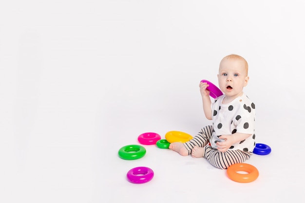 Un petit enfant de 8 mois joue sur un fond blanc isolé, développement précoce des enfants jusqu'à un an, place pour le texte
