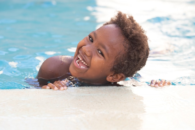 Petit enfant africain éclaboussant dans la piscine